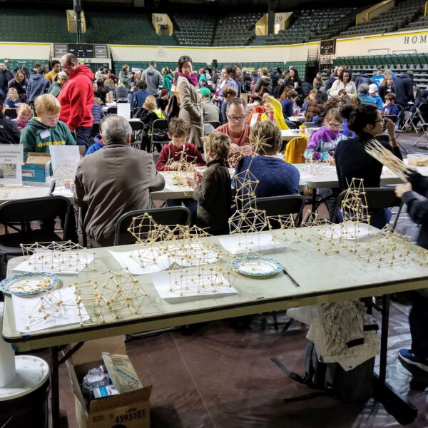 Photograph of Eugene Math Festival. Many festival goers are engaged in the many festival activities. Credit (https://blogs.uoregon.edu/mathfestival/)